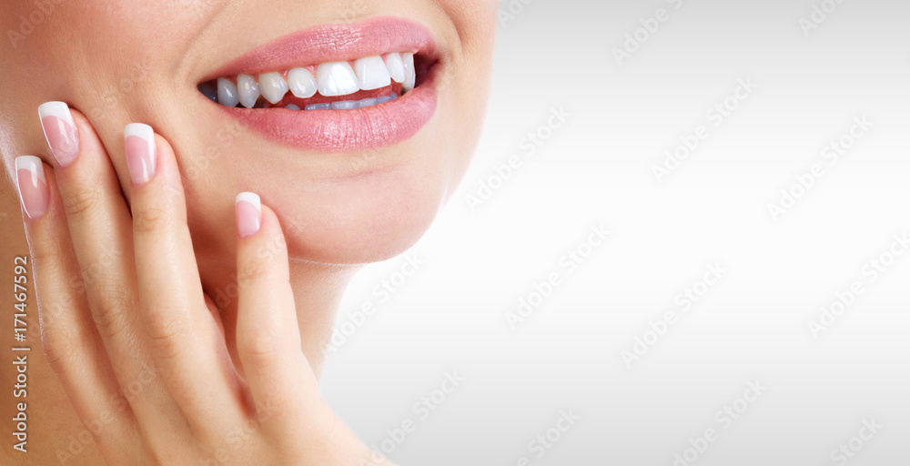 Fototapeta premium Closeup shot of woman's toothy smile against a grey background with copyspace