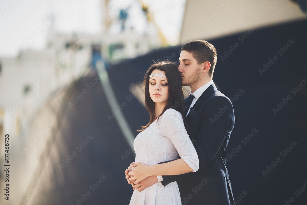 Happy bride and groom hugging near ship