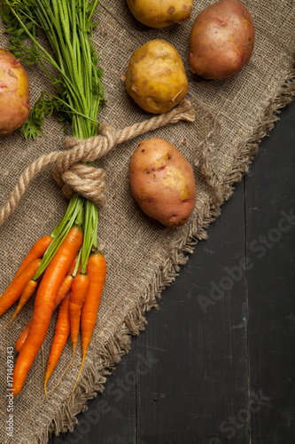 Carrots and potatoes on a black wooden background photo