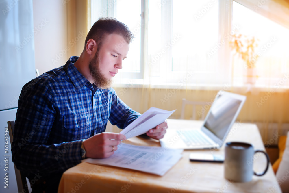 Handsome man doing some paperwork at home