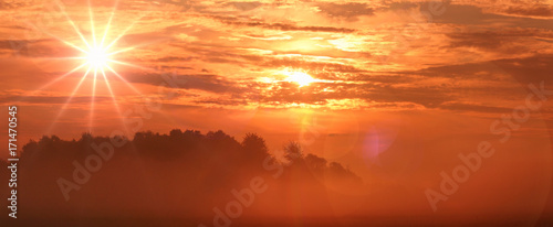 orange sunrise over meadow with morning mist