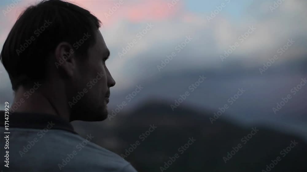 Man on mountain top looks down determined to conquer the world close up slow motion. Male head silhouette back side view at evening sky background enjoying view of success. Self-made person concept
