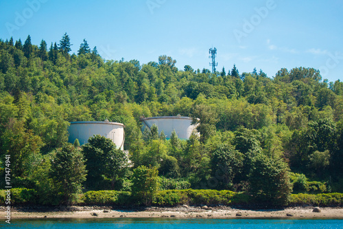 Photo of industrial site behind trees across water