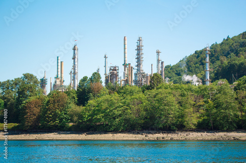 Photo of industrial site behind trees across water