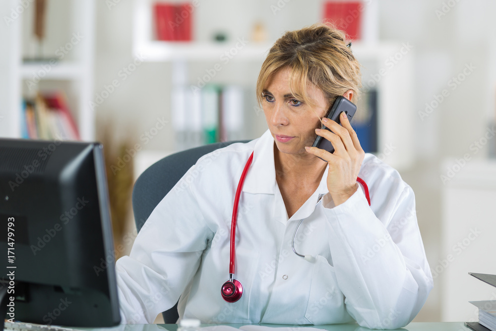 female doctor sitting at her office while phoning her patient female doctor sitting at her office while phoning her patient