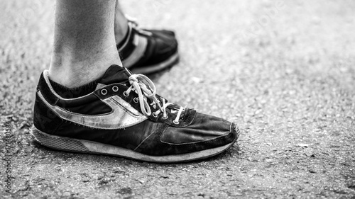 Man close up view of shoes in wet asphalt in black and white