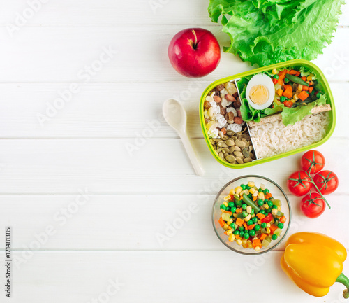 Lunch box filled with rice and mixed vegetables on white wooden background with copy space