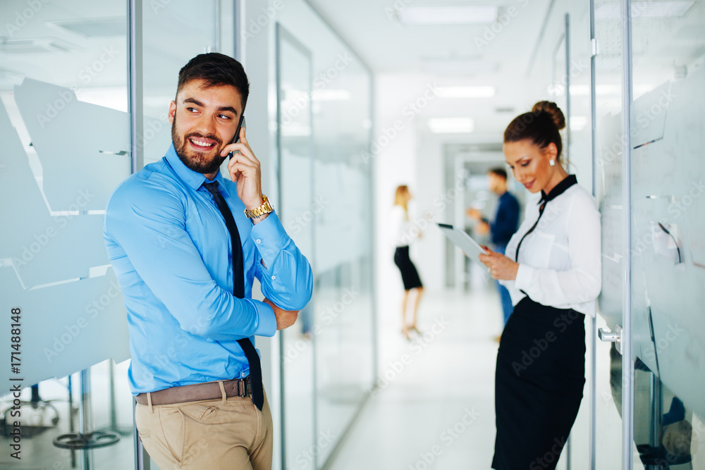 Businessman on the phone standing in hall and woman using digital tablet out of focus Businessman on the phone standing in hall and woman using digital tablet out of focus