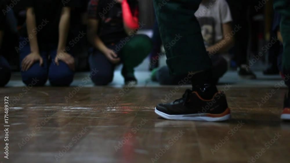 A view of the legs in black sneakers. A street dancer takes part in a dance competition in the style of hip hop. A view of the legs in black sneakers. A street dancer takes part in a dance competition in the style of hip hop.