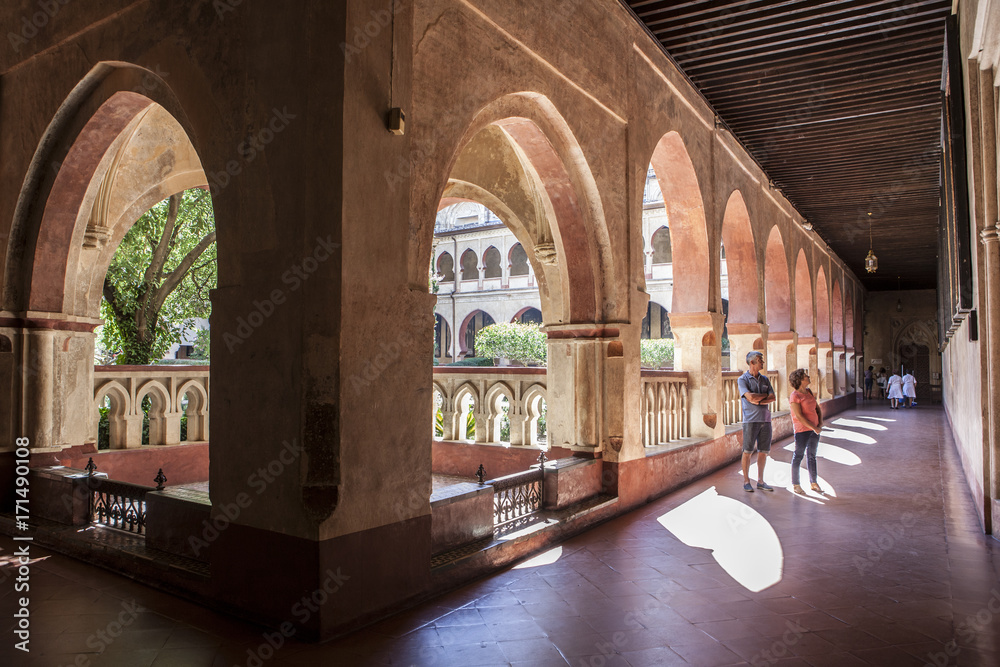 Visitors walking by mudejar cloister of Guadalupe Monastery