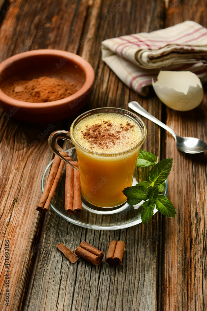 eggnog into glass cup on wooden table eggnog into glass cup on wooden table
