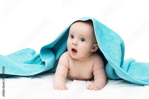 Surprised baby girl or boy, with big blue eyes and opened mounth, after shower with towel on head lying on soft blanket, isolated on white background