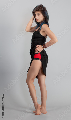 Woman Flirtatiously Pulling Up Black Dress to Reveal Red Panties © mpaphotoftl