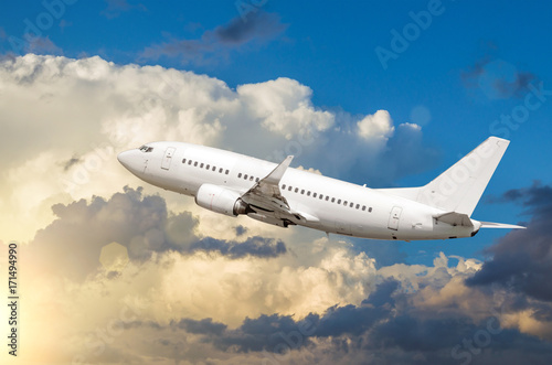 Passenger white airplane takes off against a background of cumulus clouds at sunset