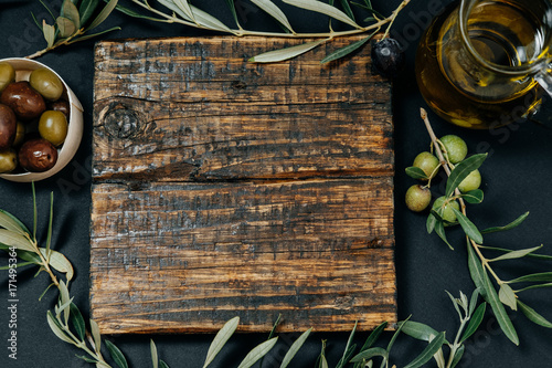 Healthy snack: Dark and green olives, oil, goat cheese on a wooden board, space for text