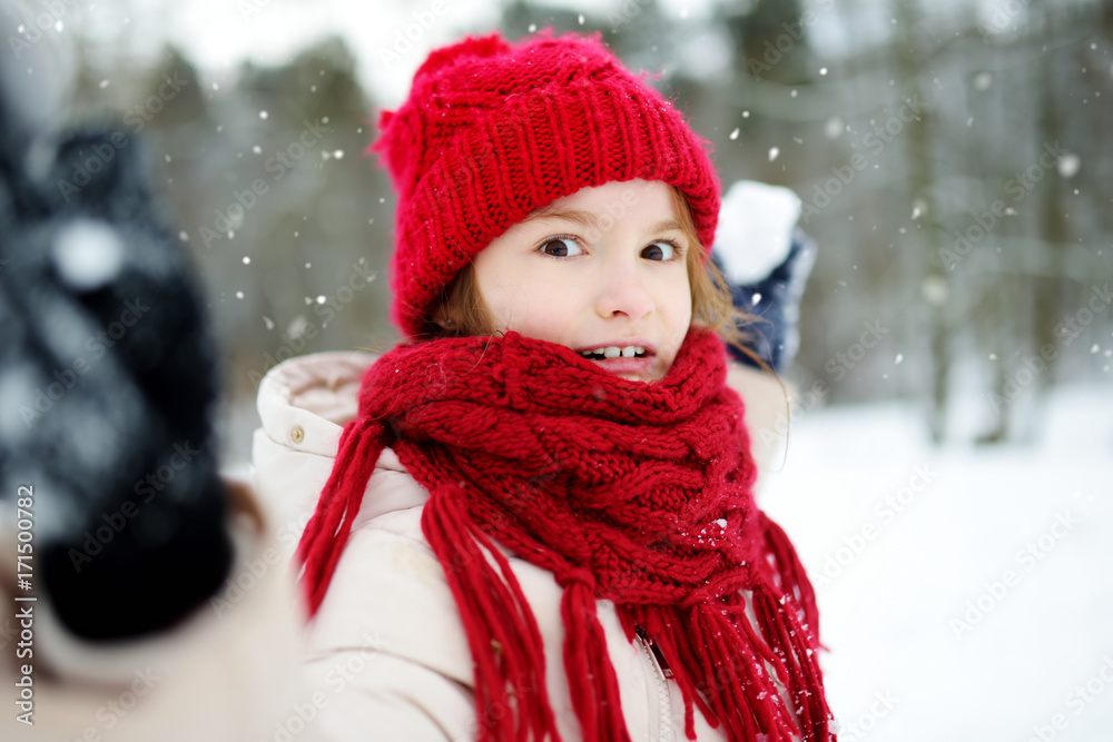 Adorable little girl having fun in beautiful winter park. Cute child playing in a snow. Adorable little girl having fun in beautiful winter park. Cute child playing in a snow.