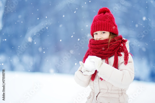 Adorable little girl having fun in beautiful winter park. Cute child playing in a snow. © MNStudio