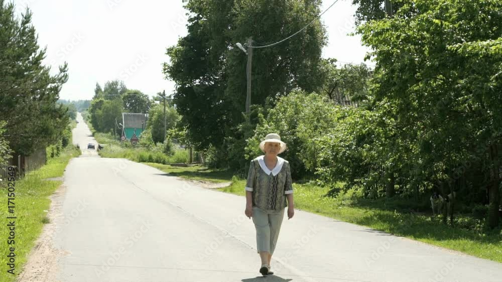 Old mature woman walking on the road at the sunny day. Positive emotions in lifestyle Old mature woman walking on the road at the sunny day. Positive emotions in lifestyle