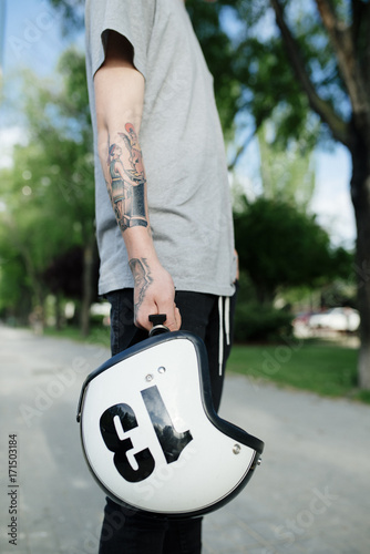 Young skater tattooed man holding a helmet photo