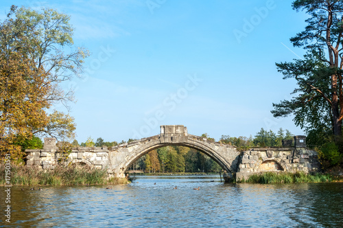 Autumn landscape with old stone hump-back bridge in Gatchina. Russia