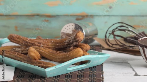 Traditional churros with hot chocolate dipping sauce on wooden counter top.