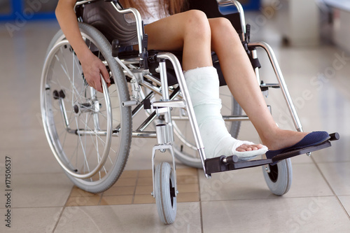 A young girl in a wheelchair is standing in the corridor of the hospital.