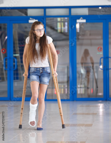 A young girl is on crutches in the corridor of the hospital.