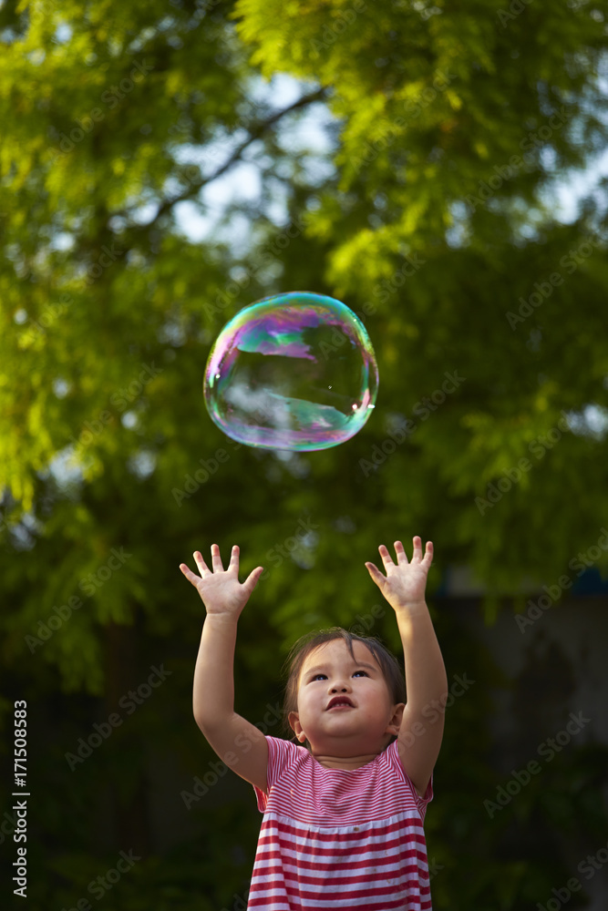 little asian girl trying to catch soap bubble little asian girl trying to catch soap bubble