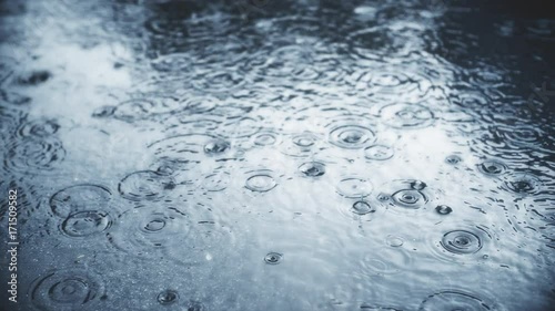 Rain falling on pavement in slow motion.