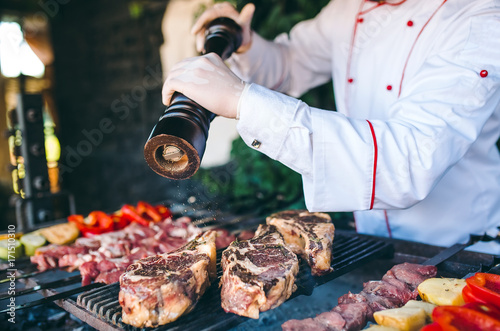 Fototapeta Naklejka Na Ścianę i Meble -  The Chef prepares meat on the barbecue.