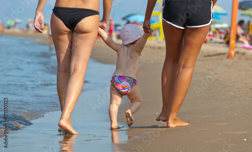 Mom teaches her daughter to walk to the beach.