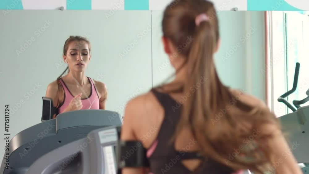 Sport girl running treadmill in front of the mirror