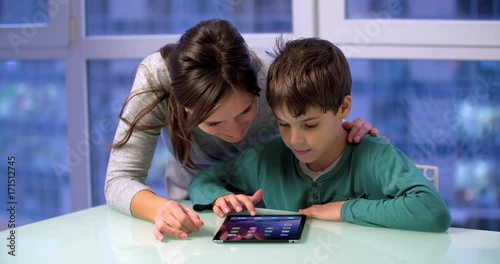Mother and son child use a tablet 4k video. Woman parent and boy kid touch mobile PC screen. Family and technology
