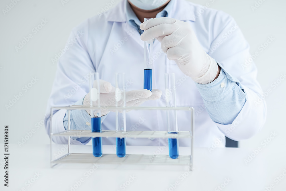 Fototapeta premium Medical or scientific researcher or man doctor looking at a test tube of clear solution in a laboratory