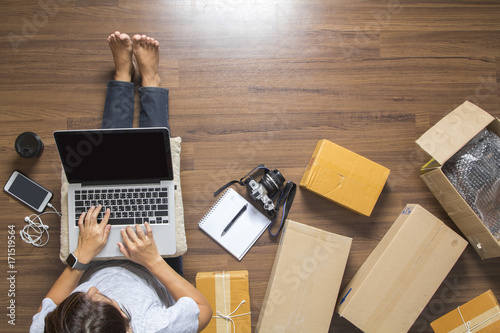 Top view of women working laptop computer from home on wooden floor with postal parcel, Selling online ideas concept