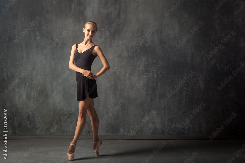 Φωτογραφία A young beautiful ballerina in a black dress, white pantyhose and pointe shoes b