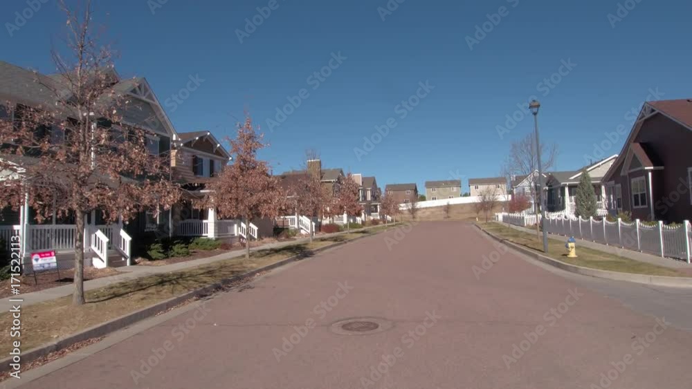 FPV, CLOSE UP: Driving past the idyllic suburban houses behind the white picket fences in sunny suburbia. Beautiful suburban neighborhood on a sunny day. Luxury real estate houses and homes in suburbs FPV, CLOSE UP: Driving past the idyllic suburban houses behind the white picket fences in sunny suburbia. Beautiful suburban neighborhood on a sunny day. Luxury real estate houses and homes in suburbs