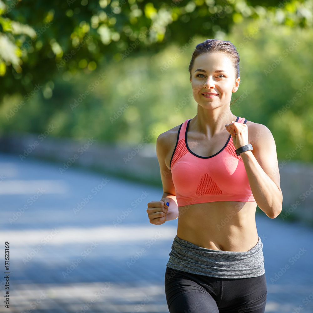 Beautiful young woman in pink top jogging in park. Healthy girl lifestyle  background with copyspace Stock Photo