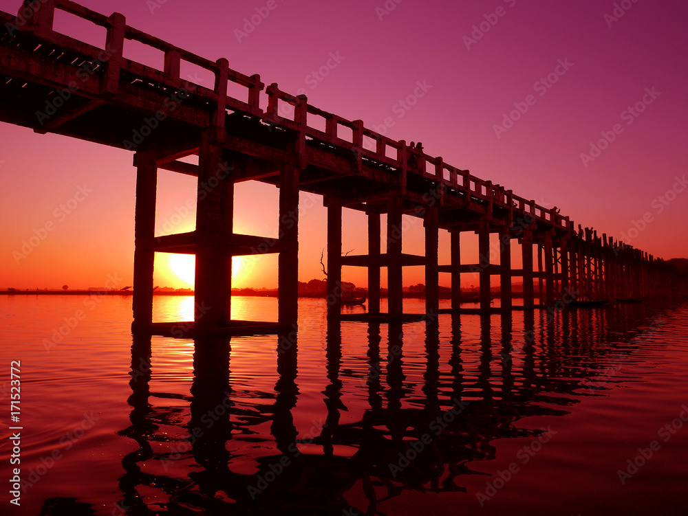 Beautiful sunset behind a long wooden bridge in Mandalay, Myanmar in red tone
