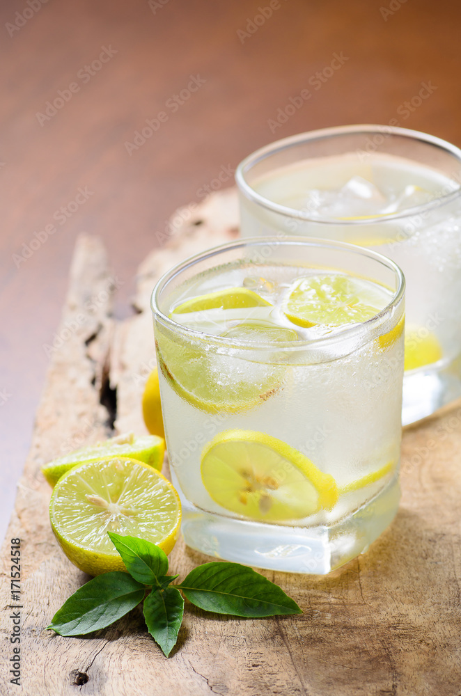 Cold lemonade with ice and fresh slice lemon in the glass on wooden plate,Healthy drink in summer Cold lemonade with ice and fresh slice lemon in the glass on wooden plate,Healthy drink in summer