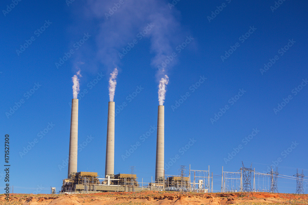 White smoke and steam spewed from coal-powered plant, profiled on deep blue sky, on a sunny day White smoke and steam spewed from coal-powered plant, profiled on deep blue sky, on a sunny day