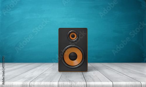 3d rendering of a one black speaker box with orange trim standing on a wooden table in front of a blue background.