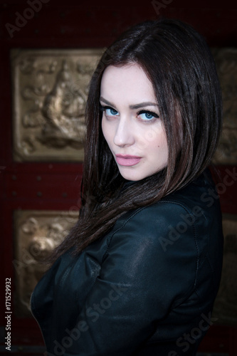 beautiful girl, brunette with blue eyes, wearing a leather jacket on a dark background