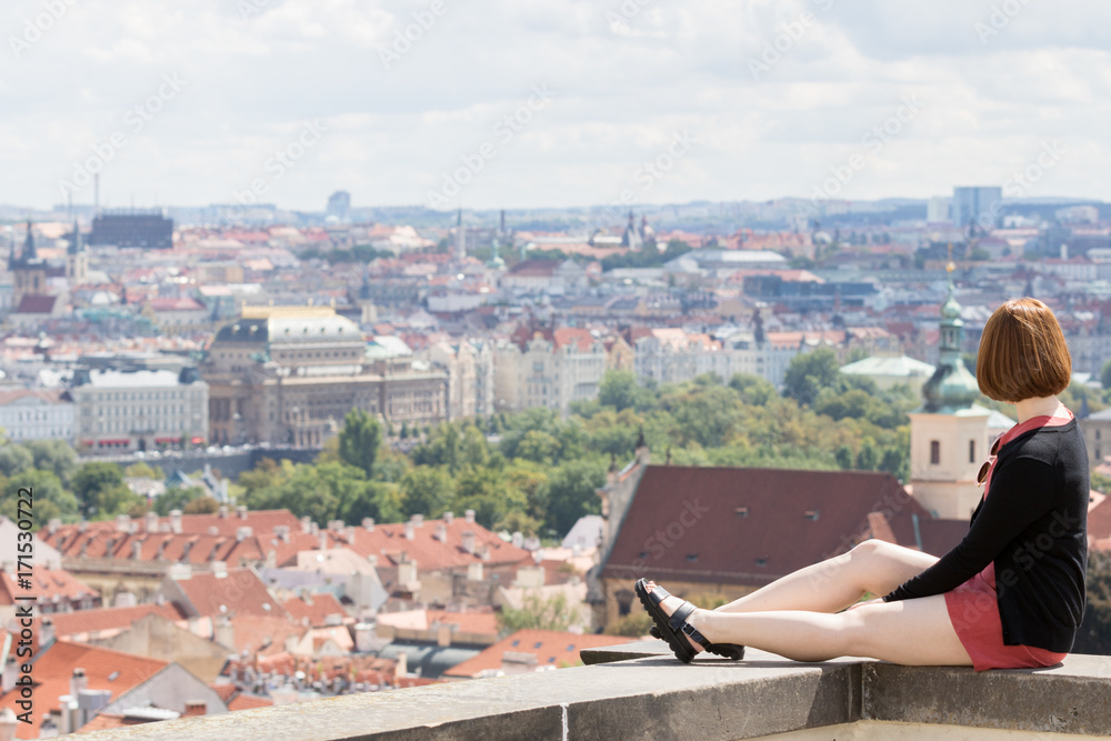 Prague, Czech Republic - August 19, 2017: Asian girl are sitting on a wall of a balcony with panoramic city views