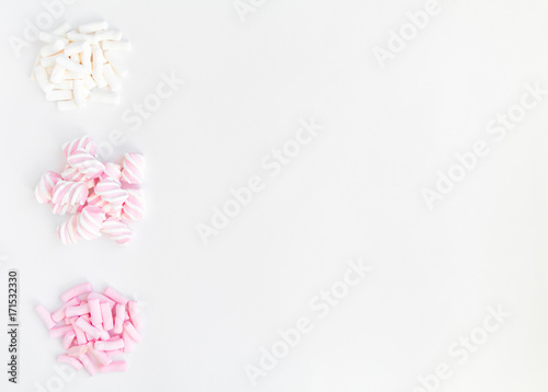 Colorful light marshmallows in groups on white background. Top view, flat lay