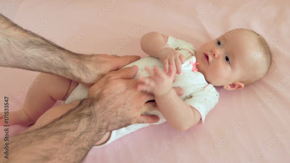 Newborn baby girl with father hands in baby crib Newborn baby girl with father hands in baby crib