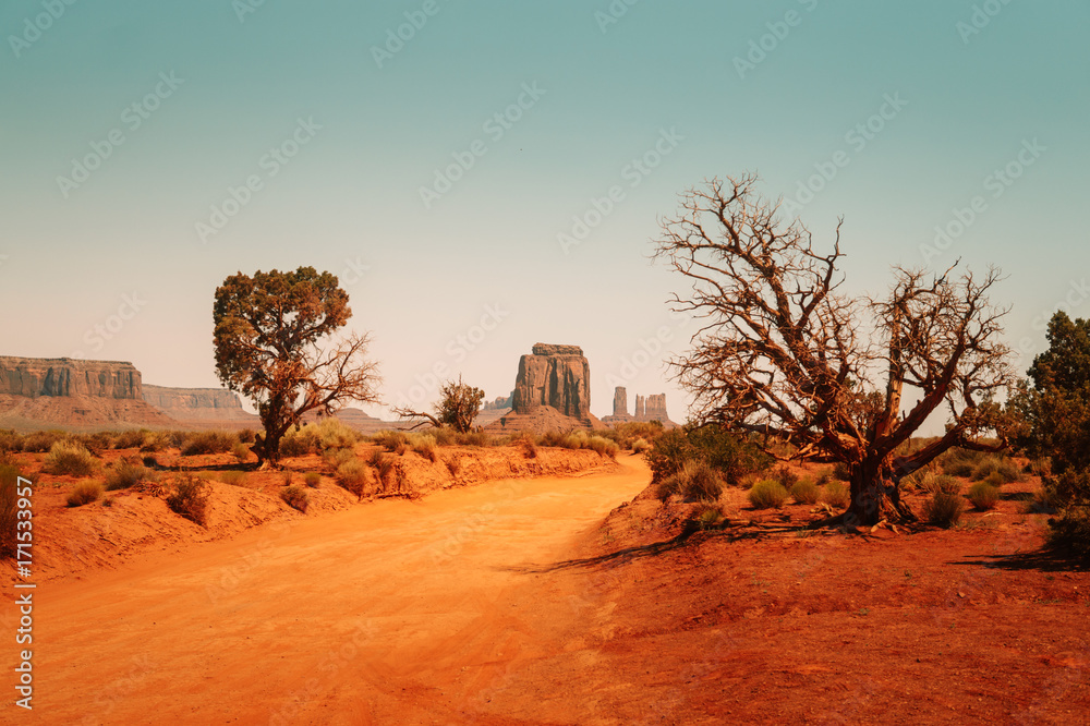 Hot desert climate of Arizona. A dirt road and rock-monuments. A dirt road in the Valley of Monuments Hot desert climate of Arizona. A dirt road and rock-monuments. A dirt road in the Valley of Monuments