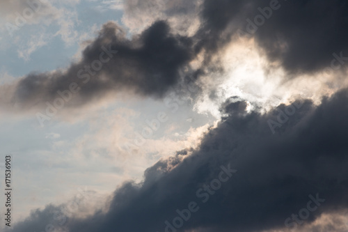 A close view of some moody and big clouds with half of the sun covered by them