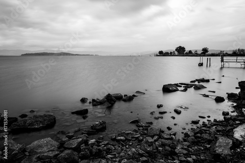 Long exposure view of a lake, with perfectly still water and stones and rocks