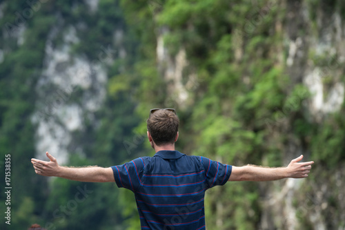 young man happy with hands rise up on beautiful lake and mountain Landscape with beautiful cloudy sky.